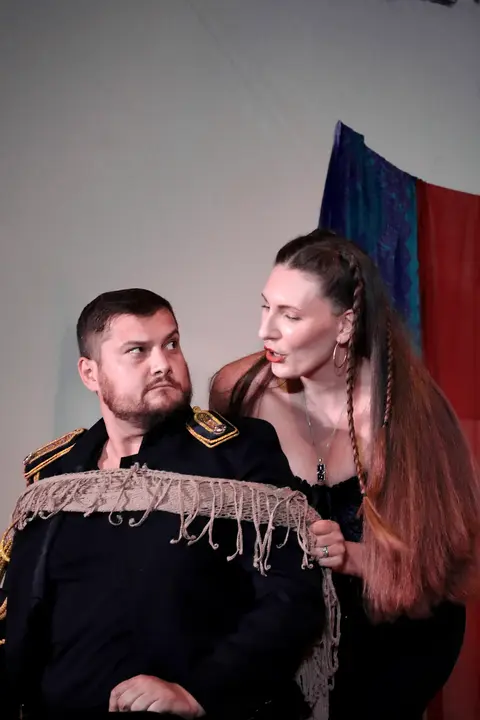 A female singer standing beside a seated singer in uniform