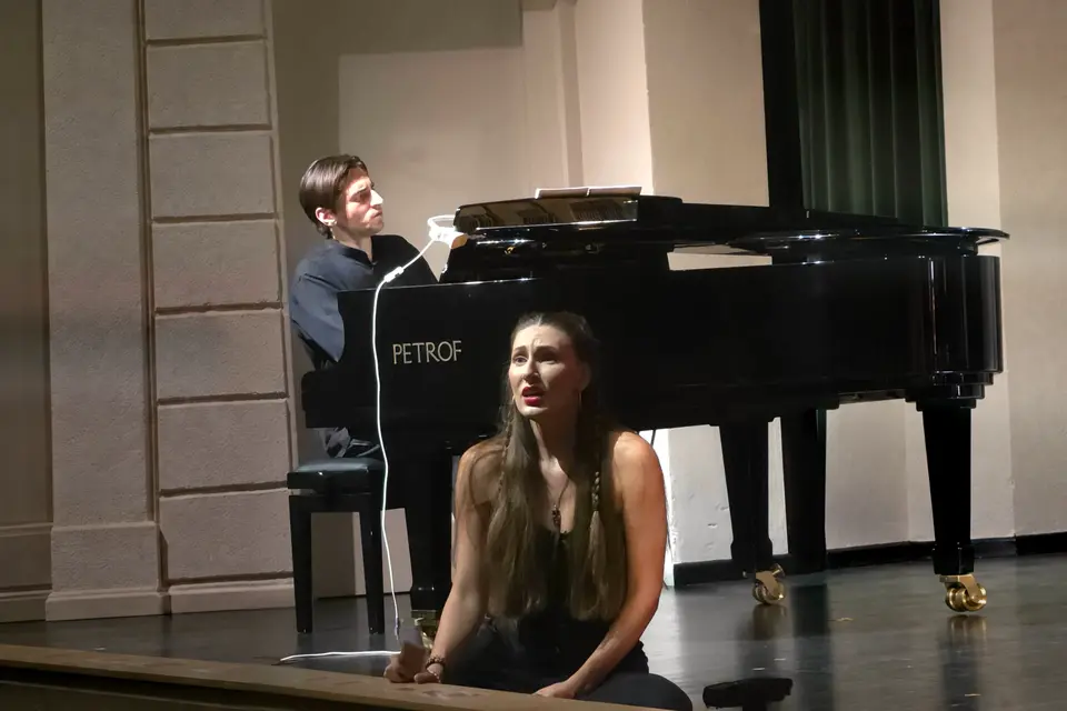 A female singer on stage with a pianist at the piano