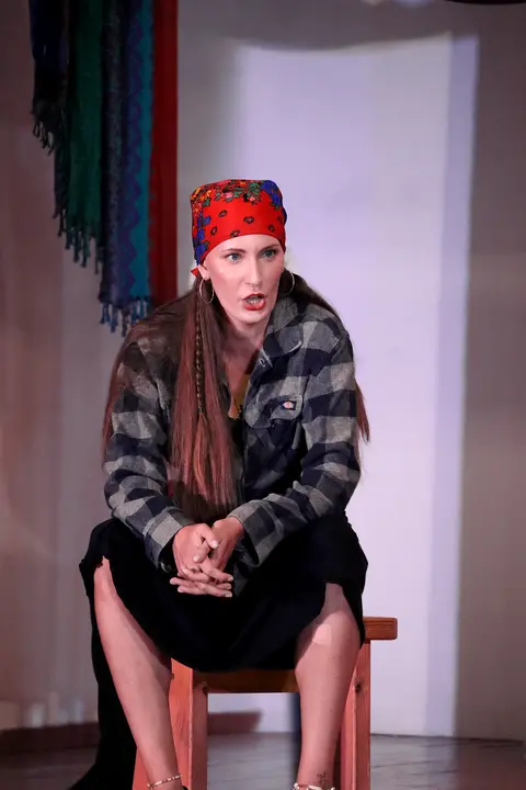 A singer in a red headscarf seated on a chair