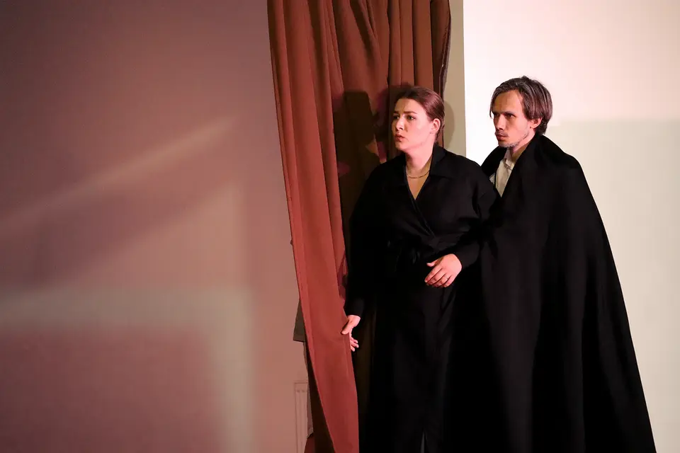Two singers in dark costumes on stage