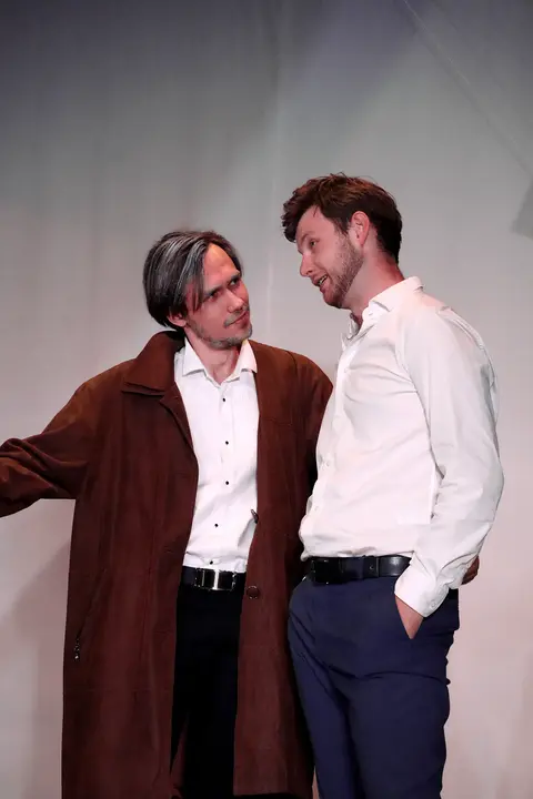 Two singers wearing a brown jacket and a white shirt