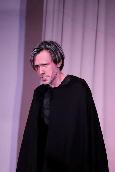 A singer wearing a black cloak